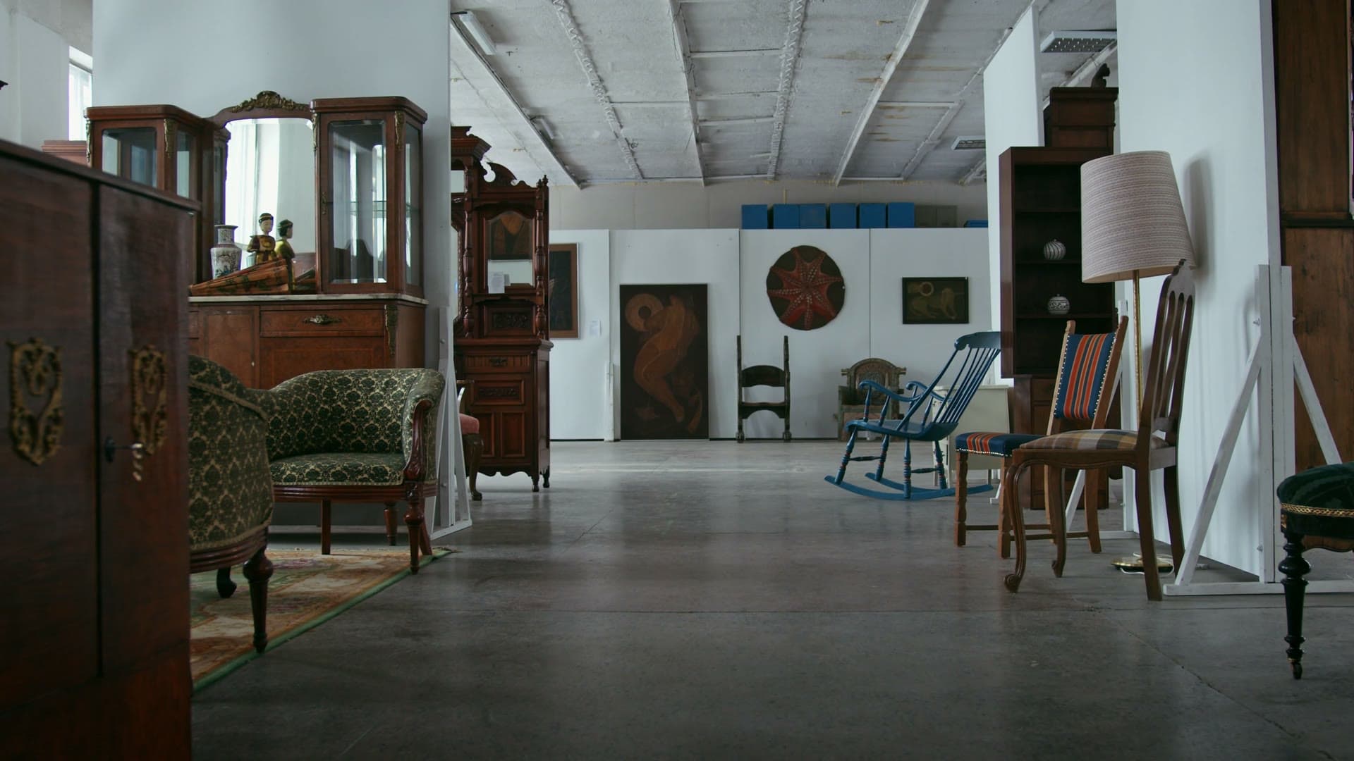 Vintage cabinets, armchairs and a blue rocking chair across an open, sunlit shop floor