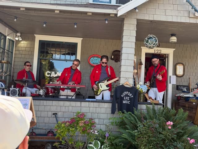 A band in 1970s red satin jackets playing on the string-lit front porch of Camp Vintage